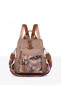 Detailed front view of brown oxford cloth backpack with colorful woven shoulder strap