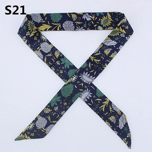 Detail of navy blue floral skinny scarf with sunflower pattern wrapped for handbag handles