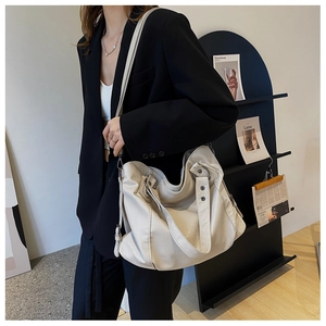 Detail of beige large capacity hobo bag with metal rivets and dual shoulder straps