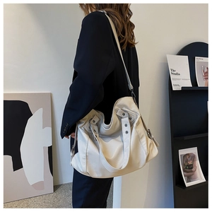 Detailed close-up of beige tote bag showing soft faux leather texture and silver rivets