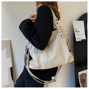 Detail of a large off-white tote bag with vintage metal rivets and dual straps for women
