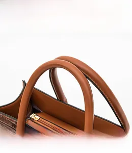 Détail d'un sac à main marron motif crocodile avec poignée en cuir lisse et zip doré