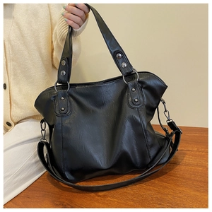 Detail of glossy black PU leather tote bag with silver studs and adjustable strap