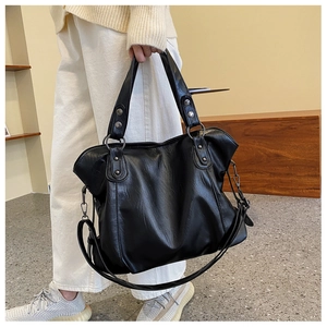 Detail of a large black tote bag with silver rivets and a detachable shoulder strap