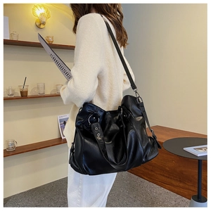 Detail of black large tote bag with silver metal rings and adjustable leather strap