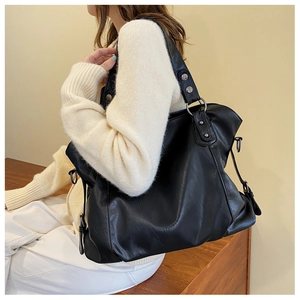Side view of large black tote bag with metallic ring details and leather texture