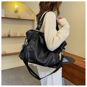Detail of minimalist black tote bag featuring soft lychee texture and metallic buckles