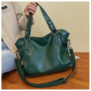 Detail of dark green pebble grain leather tote with adjustable strap on wooden table