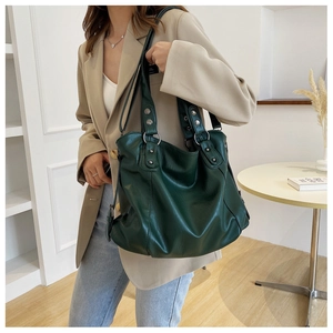 Detail of dark green tote bag featuring silver rivets and soft synthetic leather texture