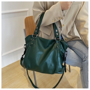 Detail of forest green leather tote bag with silver ring hardware and shoulder strap