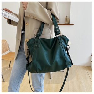 Detail of dark green PU leather tote bag with retro metal rings and shoulder strap