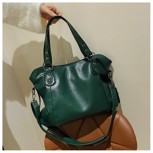 Detail view of dark green PU leather handbag with metal rivets and adjustable shoulder strap