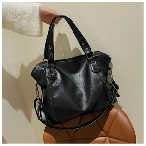 Detail of a large black vintage tote bag showing rivet accents and dual carry handles
