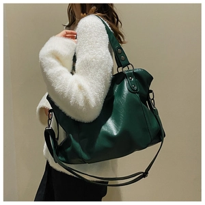 Close-up of dark green faux leather tote bag with bronze hardware and shoulder straps