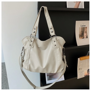 Detail of cream white tote bag with lychee texture leather and metal rivet handle strap
