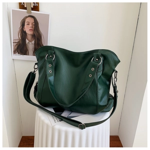 Detail of forest green PU leather handbag featuring wide handles and dark gunmetal hardware