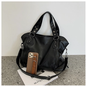 Detailed view of black large capacity tote bag featuring silver studs and adjustable strap