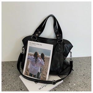 Detail shot of a black oversized tote bag with soft faux leather texture and silver rings