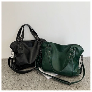 Detail of minimalist leather tote bags in black and dark green with detachable straps