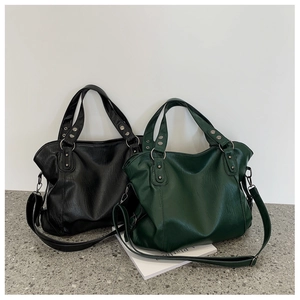 Close-up of black and green large tote bags featuring metal rivets and leather texture