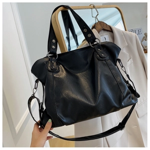 Detail of black PU leather tote bag with metallic hardware on a minimalist hanger