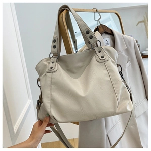 Detail view of cream beige soft leather tote bag with vintage metal rivets and long strap