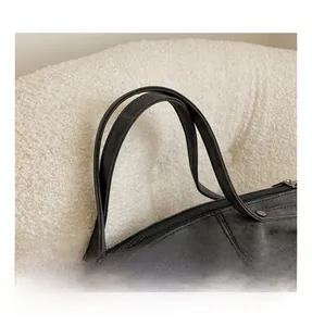 Detail shot of black faux suede tote bag featuring sturdy double handles and metal rivets