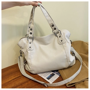Detail of cream white leather tote bag with vintage metal rivets and adjustable strap