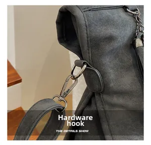 Detail of dark grey handbag showing gunmetal hardware hook and chain connection