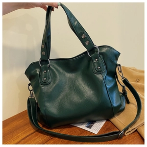 Detail of forest green tote bag featuring metallic rivets and adjustable shoulder strap