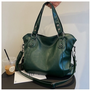 Close-up of dark green textured tote bag with metal rivets and adjustable shoulder strap