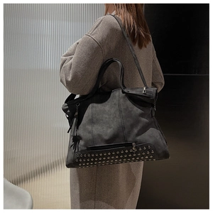 Detail of grey retro tote bag with metallic studs and fringe tassels on suede texture