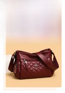 Detail of burgundy quilted leather handbag with textured diamond stitching and metallic logo