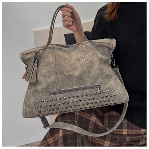 Close-up of vintage grey tote bag with metal studs, fringe detail, and large capacity