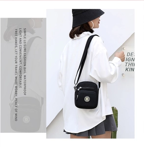 Detail of waterproof nylon crossbody bag with multiple zip pockets and logo on model