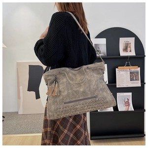Detail view of large retro tote bag with rivets and tassel on distressed taupe faux leather