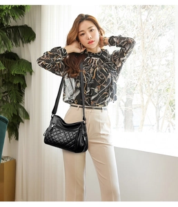 Detail of black quilted leather crossbody bag with multiple zipper pockets and kangaroo logo