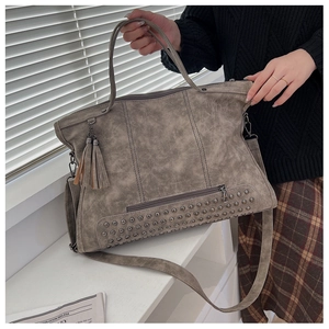 Close-up of vintage tote bag with metal studs, double tassels and top handles