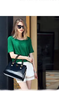 Détail d'un sac à main noir motif crocodile avec ferrures dorées et finition brillante