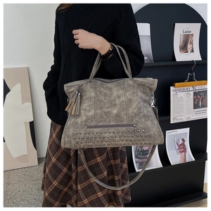 Detail view of large tote bag with studs and tassels on gray matte vintage leather