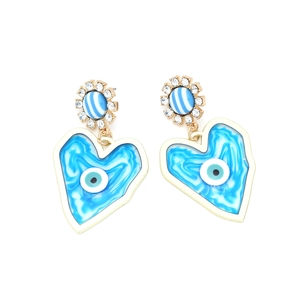 Detail of heart evil eye earrings with gold metal and sparkling crystal sunburst