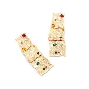 Detail of vintage tiered gold earrings with hammered texture and colorful rhinestones