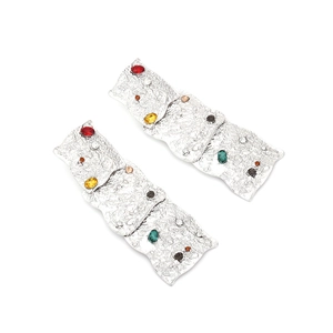 Detail of vintage silver earrings with colorful rhinestones and textured geometric squares