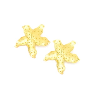 Macro view of matte gold lily flower earrings with detailed brushed metal texture