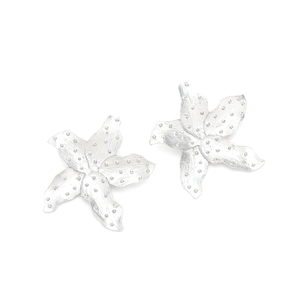 Detailed macro view of silver alloy flower earrings with matte brushed metal texture