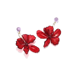 Detailed close-up of red acrylic floral earrings with purple beads and textured petals