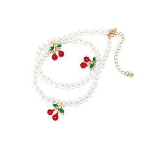 Elegant double-layered white pearl necklace with red cherry pendants and adjustable gold clasp