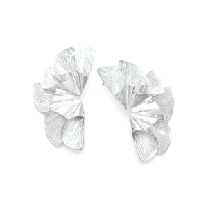 Close-up of silver fan-shaped leaf earrings with layered texture and metallic finish