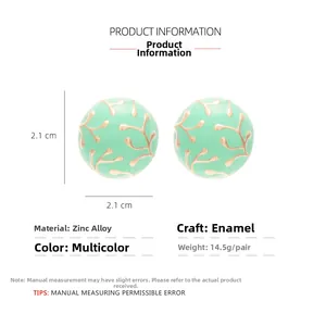 Detail of round mint green enamel earrings with gold coral patterns and 2.1cm dimensions