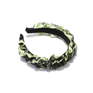 Detail of pleated green satin and black lace headband with sparkling crystal accents